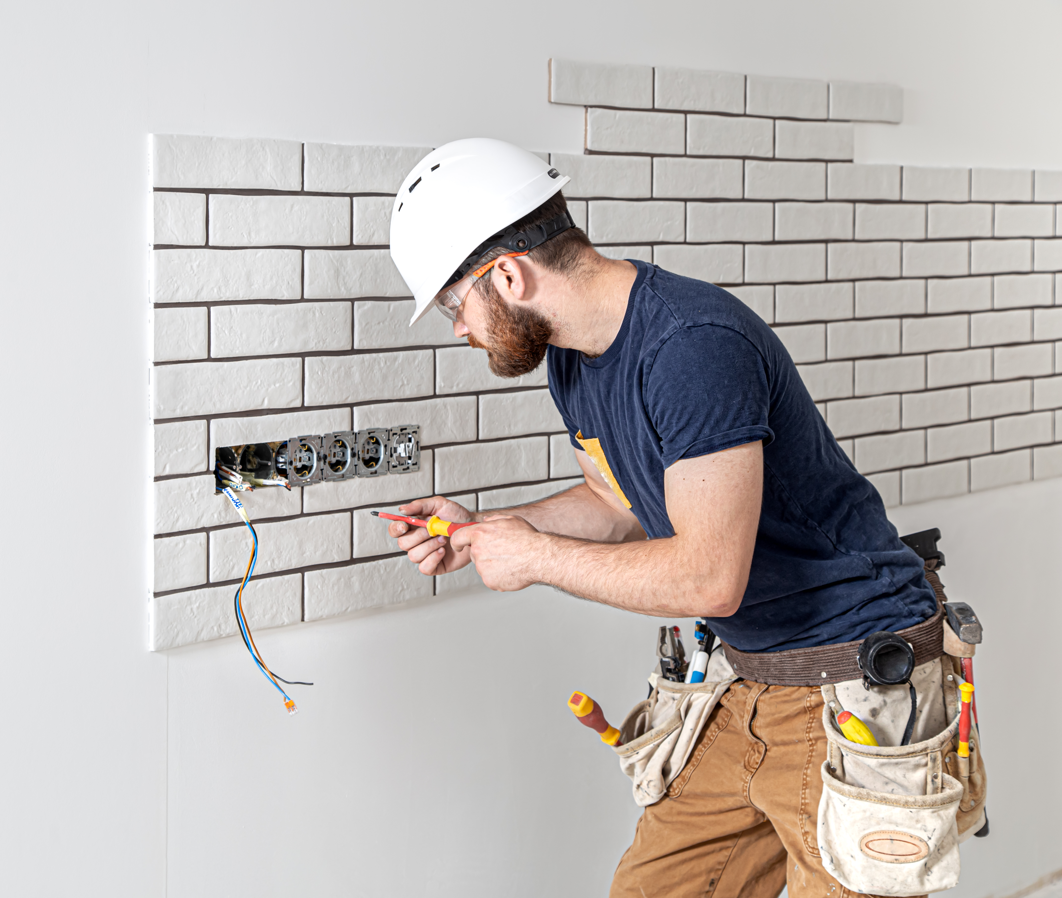 trabajador de la construccion electricista con barba en monos durante la instalacion de enchufes concepto de renovacion del hogar